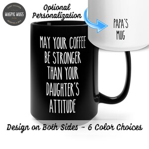 May include: Black coffee mug with white text that reads "May your coffee be stronger than your daughter's attitude". The mug has a white handle and is shown with a white mug on the back that says "Papa's Mug".