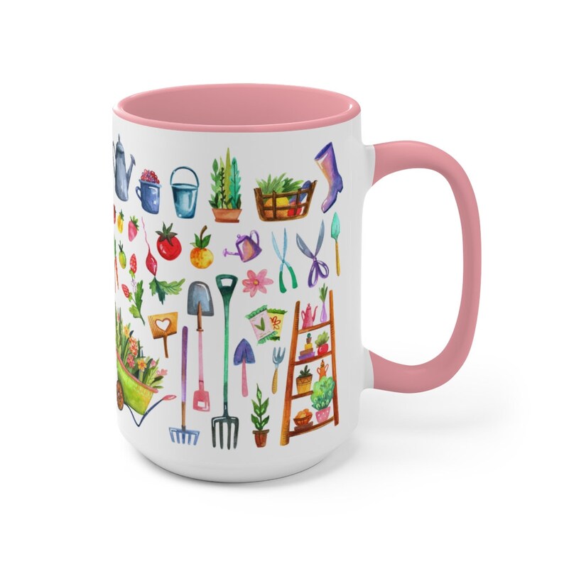 May include: White ceramic mug with a pink interior and handle. The mug is decorated with watercolor illustrations of gardening tools, plants, and vegetables. The design includes a wheelbarrow, watering can, and a small wooden ladder with potted plants.