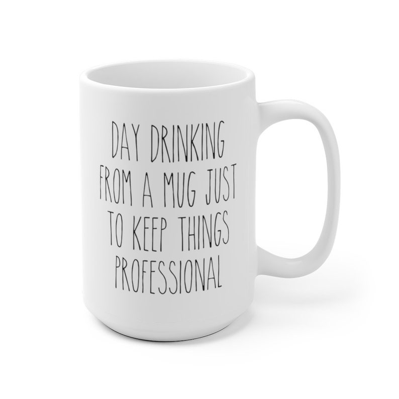 May include: White ceramic mug with a large handle. The mug features the text "DAY DRINKING FROM A MUG JUST TO KEEP THINGS PROFESSIONAL" in black, handwritten-style lettering. The mug is a standard size for coffee or tea.