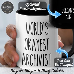 May include: White ceramic mug with black text that reads "WORLD'S OKAYEST ARCHIVIST". The mug is 11 oz or 15 oz and comes in 6 colors. The text can be personalized.