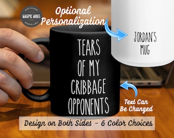 May include: Black coffee mug with white text that reads "Tears of my Cribbage Opponents". The mug is shown with a hand holding it. A white mug with the text "Jordan's Mug" is shown next to it. The text "Text Can Be Changed" is shown below the mugs. The text "Design on Both Sides - 6 Color Choices" is shown below the mugs.
