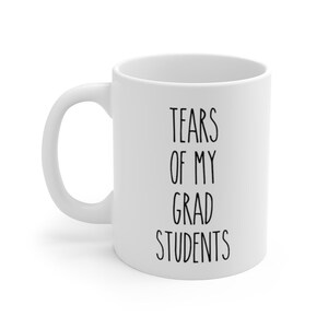 May include: White ceramic coffee mug with black text that reads "Tears of my grad students".