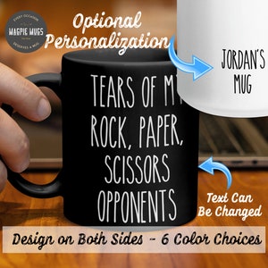 May include: Black coffee mug with white text that reads "Tears of my rock, paper, scissors opponents". The mug is shown with a hand holding it. The text "JORDAN'S MUG" is shown on a white mug in the background. The text "Text Can Be Changed" is also shown on the image. The text "Design on Both Sides - 6 Color Choices" is shown at the bottom of the image.