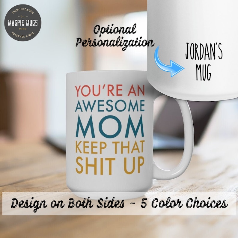 K&ouml;nnte beinhalten: Eine wei&szlig;e Keramik-Kaffeetasse mit dem Text "You're an Awesome Mom Keep That Shit Up" in bunten Buchstaben. Die Tasse hat einen Henkel und wird auf einer Holzoberfl&auml;che gezeigt. Der Text "Optionale Personalisierung" ist im Hintergrund sichtbar. Die Tasse ist in 5 Farben erh&auml;ltlich.