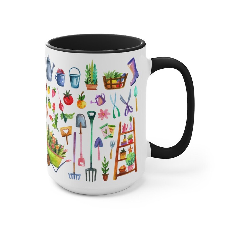 May include: White ceramic mug with a black rim and handle. The mug features a colorful illustration of gardening tools, plants, and flowers.