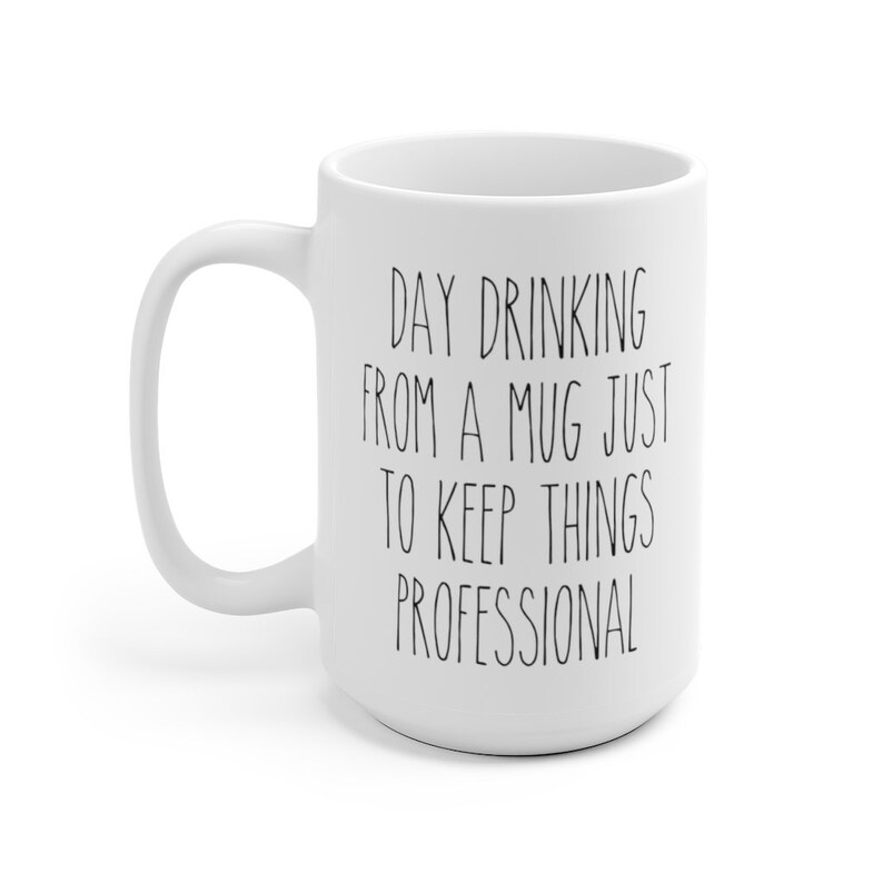 May include: White ceramic mug with a curved handle. The mug features black text that reads: "DAY DRINKING FROM A MUG JUST TO KEEP THINGS PROFESSIONAL."
