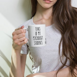 May include: White ceramic coffee mug with black text that reads "Tears of my Psychology Students".