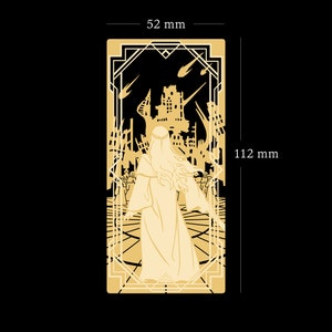 May include: A gold-colored metal bookmark with a detailed design of a woman in a long robe standing in a ruined city. The bookmark is 4.4 inches tall and 2 inches wide.