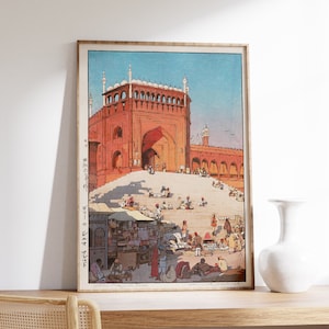 May include: A vintage woodblock print depicting a red brick building with a large archway and a bustling marketplace in front. The building has multiple domes and is surrounded by a courtyard. People are walking, shopping, and interacting in the marketplace.