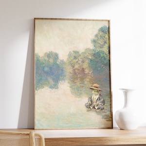 May include: A framed painting of a frog wearing a hat and sitting by a lake. The painting is in a muted color palette of blues, greens, and yellows. The background is a hazy landscape with trees and water.
