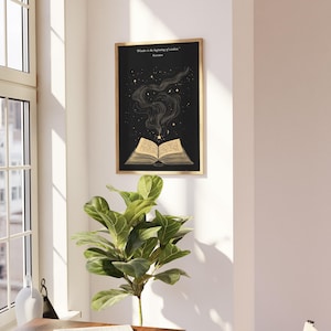 May include: A black and gold framed print with a quote by Socrates: "Wonder is the beginning of wisdom." The print features an open book with a golden glow emanating from it, surrounded by stars.