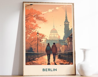 May include: A framed art print depicting a couple strolling along a path in Berlin, Germany. The artwork uses a warm colour palette with orange and yellow tones, showing buildings and trees. The word "BERLIN" is printed at the bottom.
