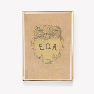 May include: A framed print of a vintage illustration featuring a stylized, grotesque face with a scroll banner that reads "E.D.A."