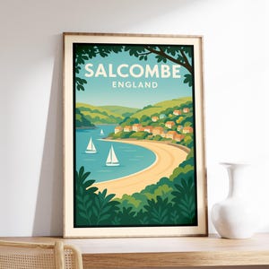 May include: A framed art print featuring a coastal scene of Salcombe, England. The print showcases a sandy beach, sailboats, and a village nestled on green hills under a blue sky. The text "SALCOMBE ENGLAND" is displayed at the top.