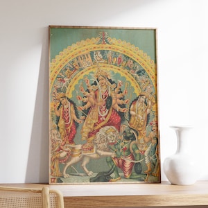 May include: A vintage print of a Hindu goddess, Durga, riding a lion. She has multiple arms and is surrounded by other deities. The print is framed in a wooden frame.