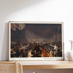 Op de afbeelding: Een ingelijst schilderij dat een historische scène voorstelt met een grote groep mensen in een kamer. Het schilderij is getiteld "Servent Du Jeu De Paume, Le 20 Juin 1760 (1791)" en wordt toegeschreven aan Jacques Louis David.