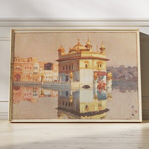 May include: A painting of a golden temple with a reflection in the water. The temple has a dome and multiple towers. The painting is framed in a light wood frame.