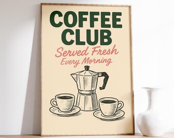 May include: A framed print with the words "COFFEE CLUB" in dark green, and "Served Fresh Every Morning" in pink. The image features a coffee maker, two cups, and saucers in black and white.