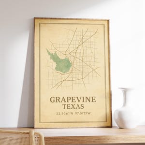 May include: A framed vintage-style map print of Grapevine, Texas, showing a green lake and road network. The text "Grapevine Texas" and coordinates are in a serif font. The print is in a brown wooden frame.