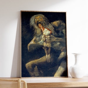 Puede incluir: Impresión enmarcada de una pintura que representa una figura devorando a otra. La obra de arte presenta una paleta de colores oscuros con una figura central con ojos muy abiertos y pelo largo, consumiendo una figura más pequeña. El marco es de color marrón claro.