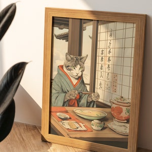 Puede incluir: Una impresi&oacute;n enmarcada de un gato vestido con un kimono japon&eacute;s tradicional, sentado a una mesa y comiendo con palillos. El gato mira al espectador con una expresi&oacute;n seria. La impresi&oacute;n est&aacute; en un marco de madera y tiene texto japon&eacute;s en la pared detr&aacute;s del gato.