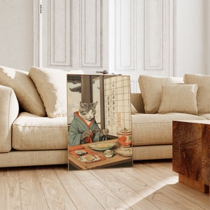 Puede incluir: Una estampa japonesa vintage en madera que representa a un gato con un kimono sentado en una mesa con un cuenco de comida. El gato est&aacute; sosteniendo palillos y hay texto en japon&eacute;s en la pared detr&aacute;s del gato. El texto dice "Un gato al que le encanta comer, un gato al que le encanta dormir, un gato al que le encanta jugar."