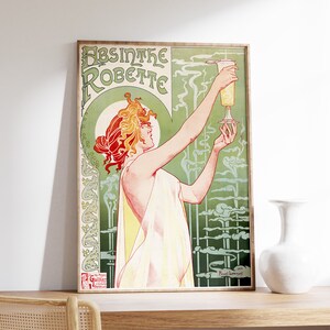 May include: Vintage poster advertising Absinthe Robette, a green liquor. The poster features a woman in a white dress holding a glass of absinthe. The background is a green and white design with a stylized floral pattern.
