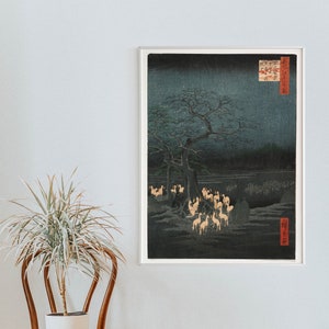 May include: A woodblock print depicting a night scene with a large tree and a group of deer in the foreground. The sky is dark blue with white stars and the deer are illuminated in a warm, golden light. The print is framed in a white frame.
