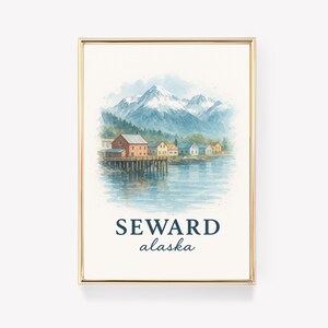 May include: A framed watercolor print of Seward, Alaska, featuring a coastal town with colorful buildings on a pier, snow-capped mountains, and the text "SEWARD alaska" in navy blue.