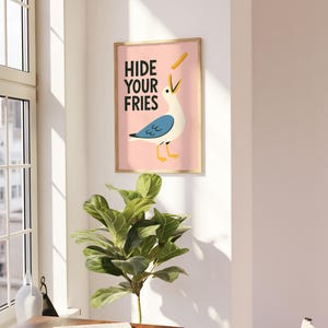 a picture of a bird hanging on a wall next to a potted plant