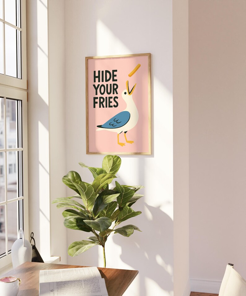 a picture of a bird hanging on a wall next to a potted plant