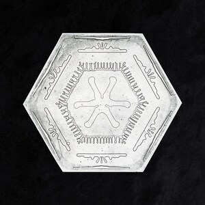 May include: A white hexagonal snowflake with a six-pointed star design in the center. The snowflake has a detailed, intricate border.