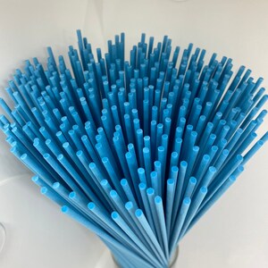 May include: A bundle of light blue diffuser sticks in a clear glass jar. The sticks are arranged in a fan shape.