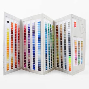 May include: A color chart with multiple pages showing a variety of thread colors. The chart is folded and the pages are fanned out.