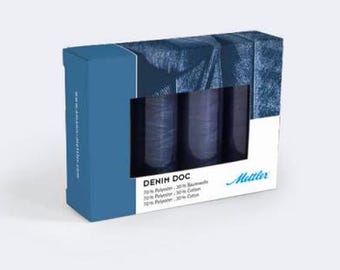 May include: A box set of denim-colored thread spools. The box is blue and white with the text "DENIM DOC" and "Metter" printed on it. The thread spools are visible through a rectangular window.