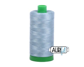 May include: A spool of light blue thread with a green base and top. The thread is tightly wound, and the spool has the Aurifil logo on the side. Ideal for sewing and quilting projects.
