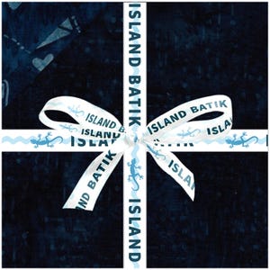 May include: A dark blue batik fabric background is adorned with a white ribbon featuring the text "ISLAND BATIK" in a vertical and horizontal cross pattern. The ribbon also has a light blue wavy design and lizard illustrations.