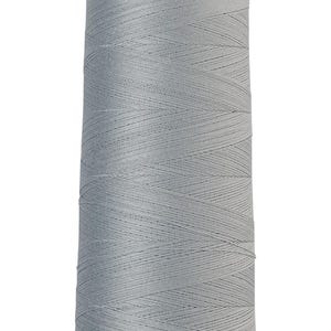 May include: A spool of light blue thread with the text "AMANN Group Mettler 100% Cotton merc." The thread is tightly wound around a brown cardboard core. The thread is a solid, pale blue color.