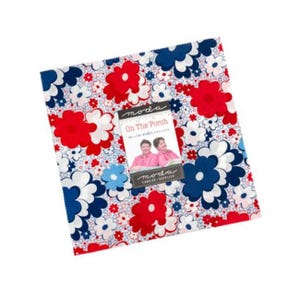 May include: A square stack of fabric squares featuring a floral pattern in red, navy blue, and white. A paper label on the front displays the text Moda, On The Porch, and shows a photograph of two people wearing pink shirts.