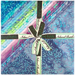 May include: A stack of colorful batik fabric squares in shades of blue, green, and purple, tied with a ribbon that reads "Island Batik". The fabric has various patterns and textures, creating a visually appealing bundle for quilting or crafting projects.