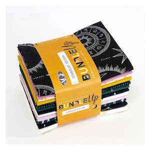 May include: A bundle of 12 half-yard fabric pieces featuring a celestial theme. The fabric is black with white constellations, stars, and zodiac symbols. The bundle is wrapped in yellow packaging with the text "Bundle Up Stardust Edition" printed on it.