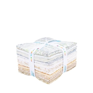 May include: A stack of fabric squares in various shades of white, beige, and green, tied with a white ribbon. The ribbon has colorful text and leaf designs. The fabric squares are neatly stacked, creating a visually appealing bundle.