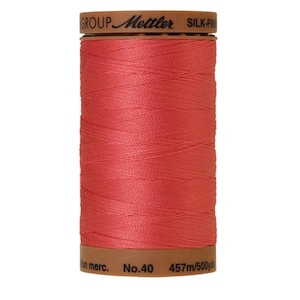 May include: A spool of coral-colored thread labeled "Metler Silk-Finish No.40 457m/500yds"