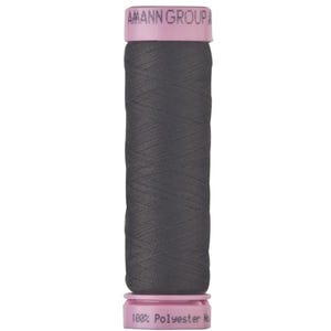 May include: A spool of dark gray sewing thread with light pink plastic ends. The top end features the text AMANN GROUP, and the bottom end displays the text 100% Polyester No. The thread is wound tightly around the central cylindrical core.