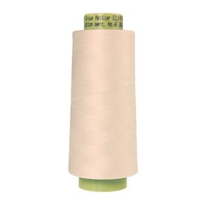 May include: A spool of beige thread with a green label that reads "Group Mettler SILK-F Cotton merc. No. 60 3000m".
