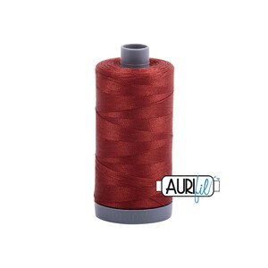 May include: A spool of dark red thread, ideal for sewing and quilting projects. The thread is tightly wound on a cylindrical spool with a gray base and top. The brand name "AURIfil" is visible on the spool.