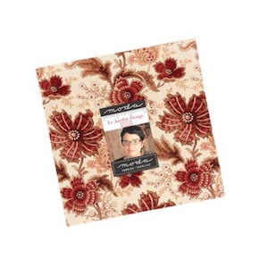 May include: A square stack of fabric squares featuring a cream background with a repeating pattern of dark red flowers and brown foliage. A central label displays the text moda, Le Jardin Rouge, and a small photograph of a person wearing glasses.