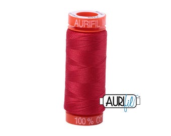 May include: A spool of red Aurifil cotton thread. The spool has a red body and a bright orange top and bottom. The text "AURIFIL" is printed on the top of the spool. The bottom of the spool reads "100% CO".