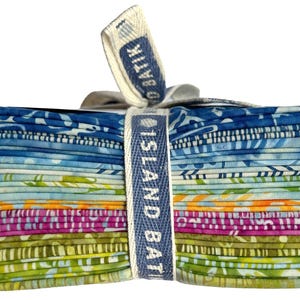 May include: A stack of colorful fabric squares, featuring a variety of patterns in shades of blue, green, pink, and orange. The fabric is tied with a white ribbon and a blue label that reads "ISLAND BATIK".
