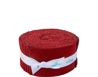 May include: A roll of red fabric strips, tightly wound and secured with a white ribbon. The ribbon features the text "Riley Blake Designs" in a teal font. The fabric appears to be a textured material, possibly felt or flannel.